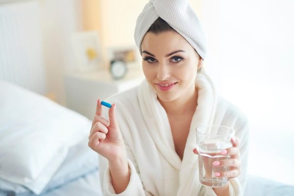 Frau, die eine Kurkuma-Pille einnimmt